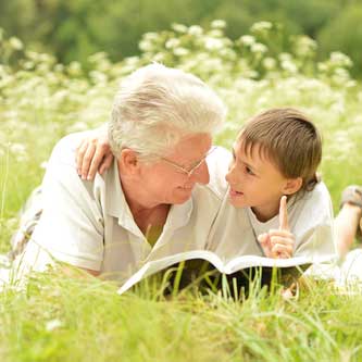 Man and child reading book in the grass